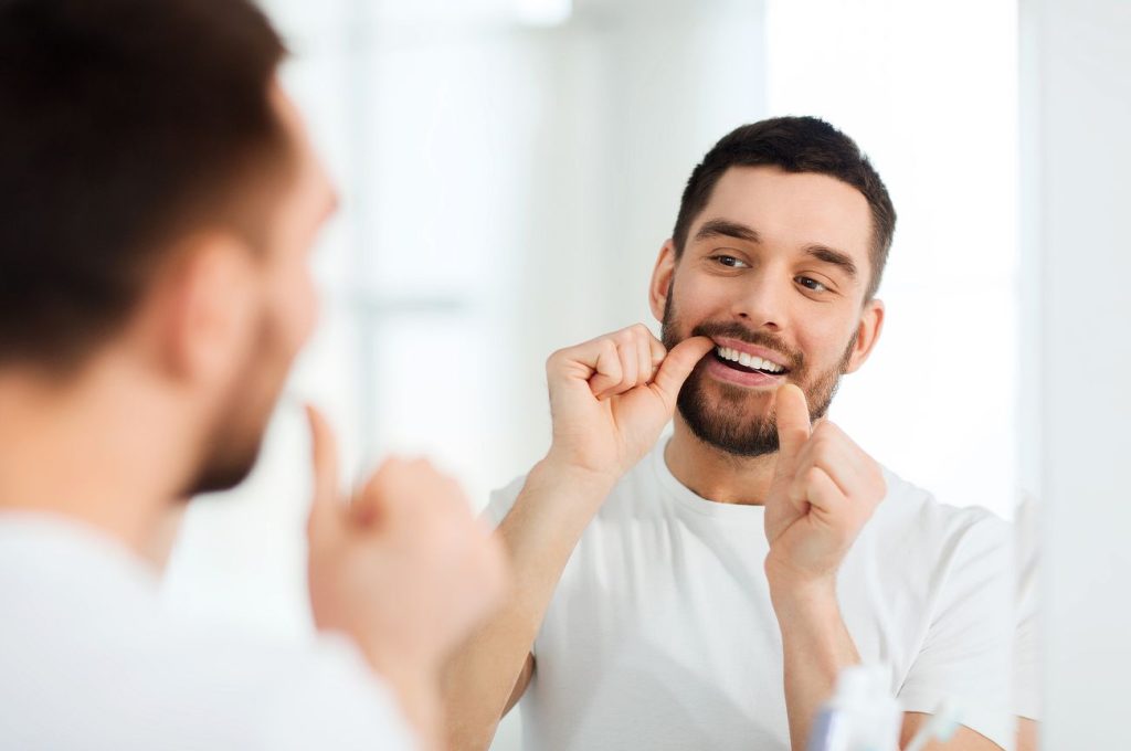 A man practising good oral hygiene by flossing his teeth